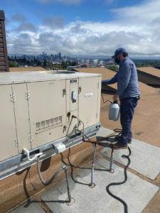 AN HVAC technician cleaning a rooftop unit